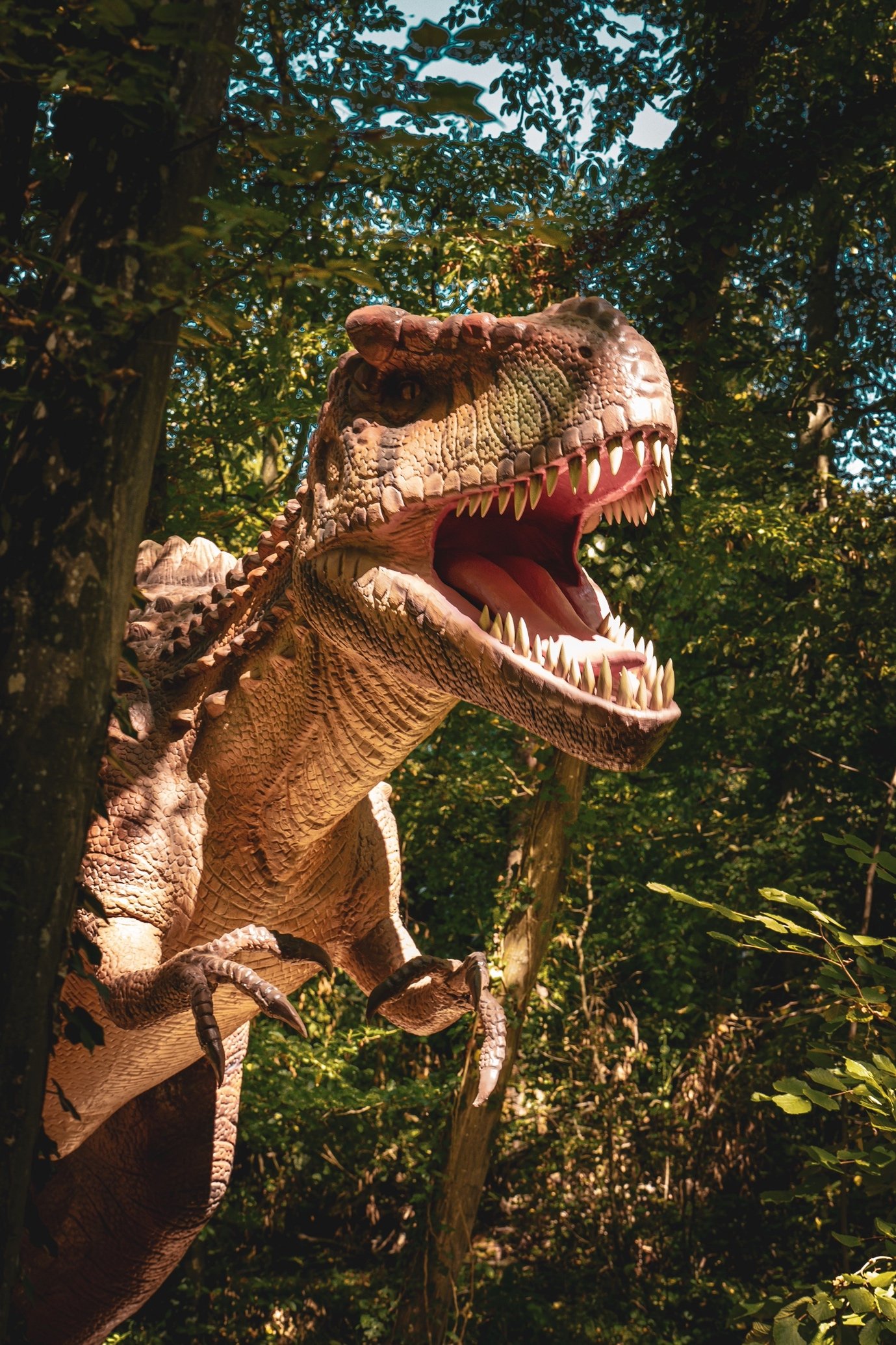 Modell eines Tyrannosaurus rex mit offenem Maul zwischen Bäumen